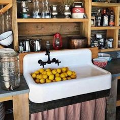 a white sink sitting in the middle of a kitchen next to a wooden shelf filled with dishes