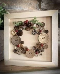 a white frame with buttons and pine cones in the shape of a wreath on it