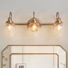 a bathroom vanity with two lights and a mirror on the wall next to it,