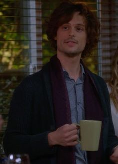 the young man is holding a coffee cup