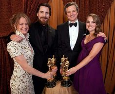 three women and one man posing with their oscars trophies in front of red curtains