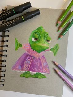 a drawing of a frog in a pink dress and some colored pencils next to it