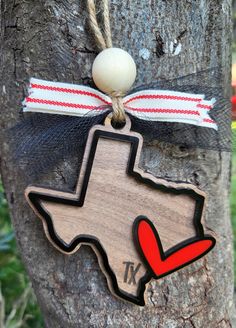 a wooden texas ornament hanging on a tree with a red and white ribbon