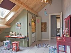 an attic bedroom with lots of toys and decorations on the floor, including a desk