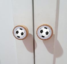 two doors with soccer balls on them are painted white and wood trimming the door