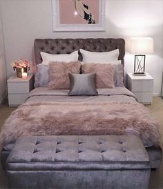 a bedroom with a bed, ottoman and pictures on the wall above it that is decorated in pink and grey tones