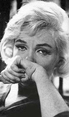 an old black and white photo of a woman with her hand on her face looking at the camera