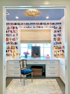 a room with a desk, chair and window covered in bookshelves on the wall