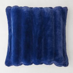 a blue fur pillow sitting on top of a white wall