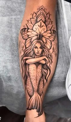 a woman's leg with a tattoo design on it and a mermaid hugging her arm