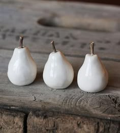 three small white pears sitting on top of a wooden table next to each other