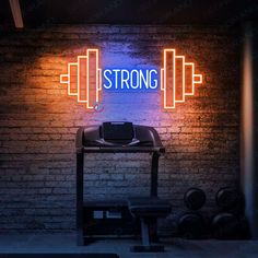 a neon sign that says strong on the side of a brick wall next to a barbell