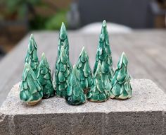 five small green trees sitting on top of a cement block in front of a table