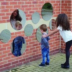 a woman and two children standing in front of a brick wall with circles on it