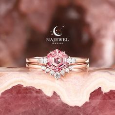 a pink diamond ring sitting on top of a marble slab next to a crescent moon