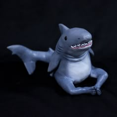 a toy shark sitting on the ground with it's mouth open