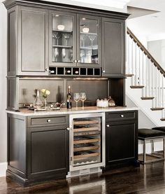 a kitchen with black cabinets and stainless steel counter tops in the middle of it, along with stairs leading up to the second floor