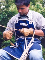 a man sitting on top of a tree holding a pair of scissors