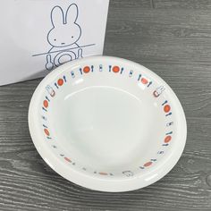 a white plate sitting on top of a wooden table next to a paper with an image of a bunny