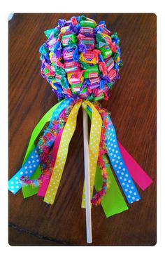 a candy lollipop on a stick with polka dots and rainbow ribbons around it