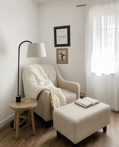 a living room with a chair, ottoman and lamp next to a window in the corner