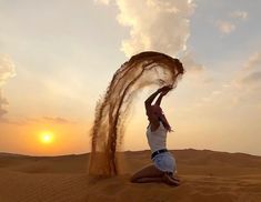 a man is throwing sand into the air on top of his head in the desert