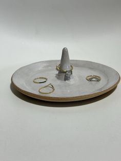 a white plate with gold rings on it and a ring holder in the shape of a cone