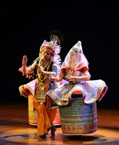 two women in colorful costumes are dancing on stage