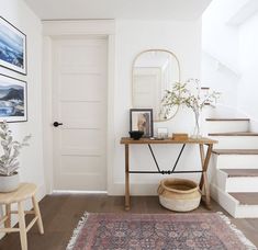 there is a rug and some pictures on the wall in this living room with stairs