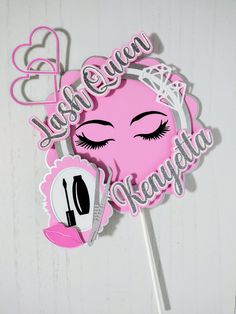 a pink cake topper with an eyeliner and lashes on it