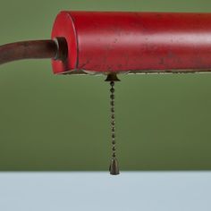 a red pipe is connected to a metal spigot with a chain hanging from it