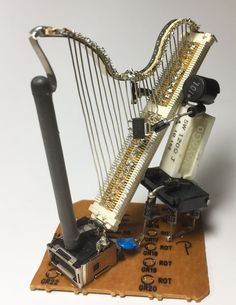 a miniature musical instrument is on top of a piece of cardboard and wires are attached to the strings