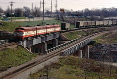 a train traveling over a bridge next to a lush green field