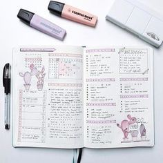 an open planner with markers and pens next to it