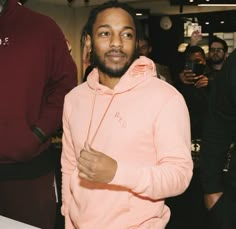 a man in a pink hoodie standing next to a table