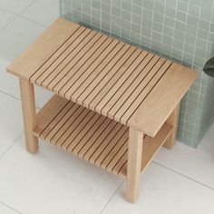 a wooden table sitting on top of a tiled floor next to a potted plant