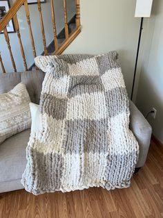 a gray and white blanket sitting on top of a couch next to a stair case