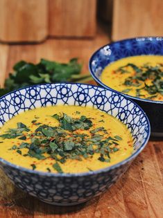 two bowls filled with soup on top of a wooden table