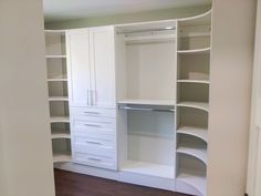 an empty closet with white shelves and drawers