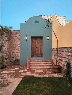 a blue building with a palm tree in front of it and brick steps leading up to the door