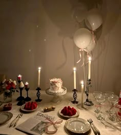 the table is set with candles, plates and desserts