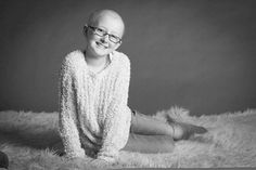 a black and white photo of a smiling woman wearing glasses sitting on a furry rug