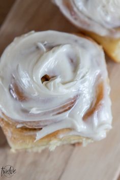 two glazed donuts sitting on top of a wooden cutting board