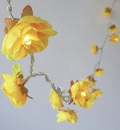 a yellow flower is hanging from a branch with lights on the top and below it