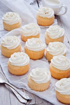 cupcakes with white frosting sitting on top of a napkin next to a spoon