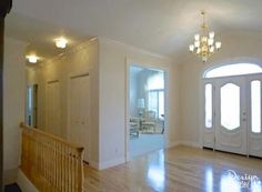 an empty living room with wood floors and white doors, chandelier and windows