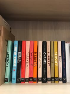 a row of books sitting on top of a wooden shelf next to a cardboard box