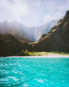 the water is very blue and green with mountains in the background