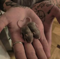 a person holding a tiny mouse in their hand with tattoos on it's arm