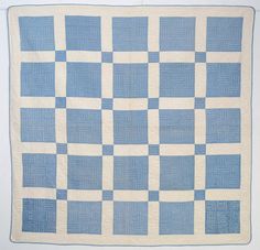 a blue and white quilt hanging on a wall